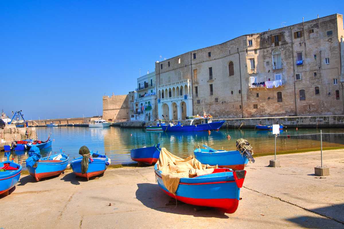 Scorcio suggestivo nei vicoli del centro storico di Monopoli, con archi in pietra, case bianche e fiori ai balconi, atmosfera mediterranea