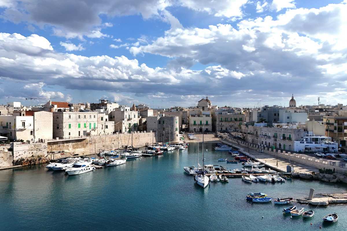 Tramonto sulla costa di Monopoli visto da una caletta, mare calmo, scogli, ombre lunghe, atmosfera romantica